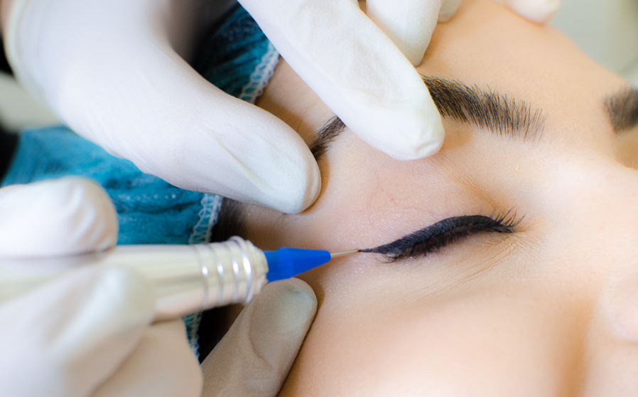 Cosmetologist applying permanent make up eyeliner, eyeliner tattoo procedure